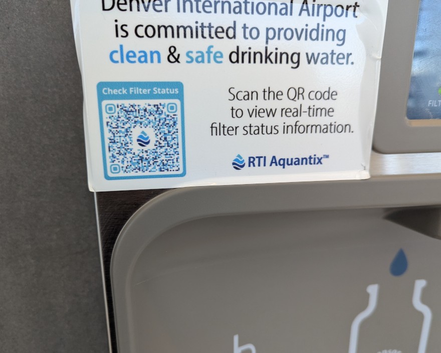 Closeup of the taller drinking fountain: "Denver International Airport is committed to providing clean & safe drinking water. Scan the QR code to view real-time filter status information. RTI Aquantix™"